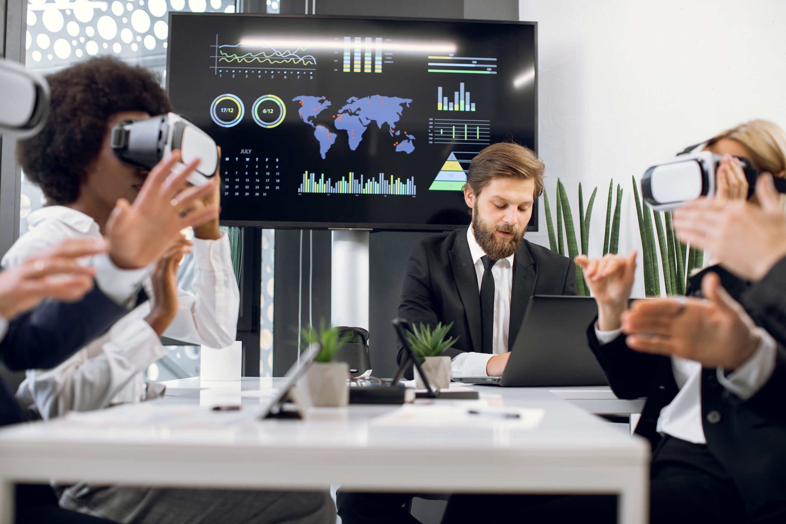 Digital Marketing Agency People in an office meeting use VR headsets while a man works on a laptop, analyzing data. Graphs and a map shine on the screen behind them, perhaps illustrating why local SEO is important for the growth of innovative businesses in today's digital landscape. Paradox Media