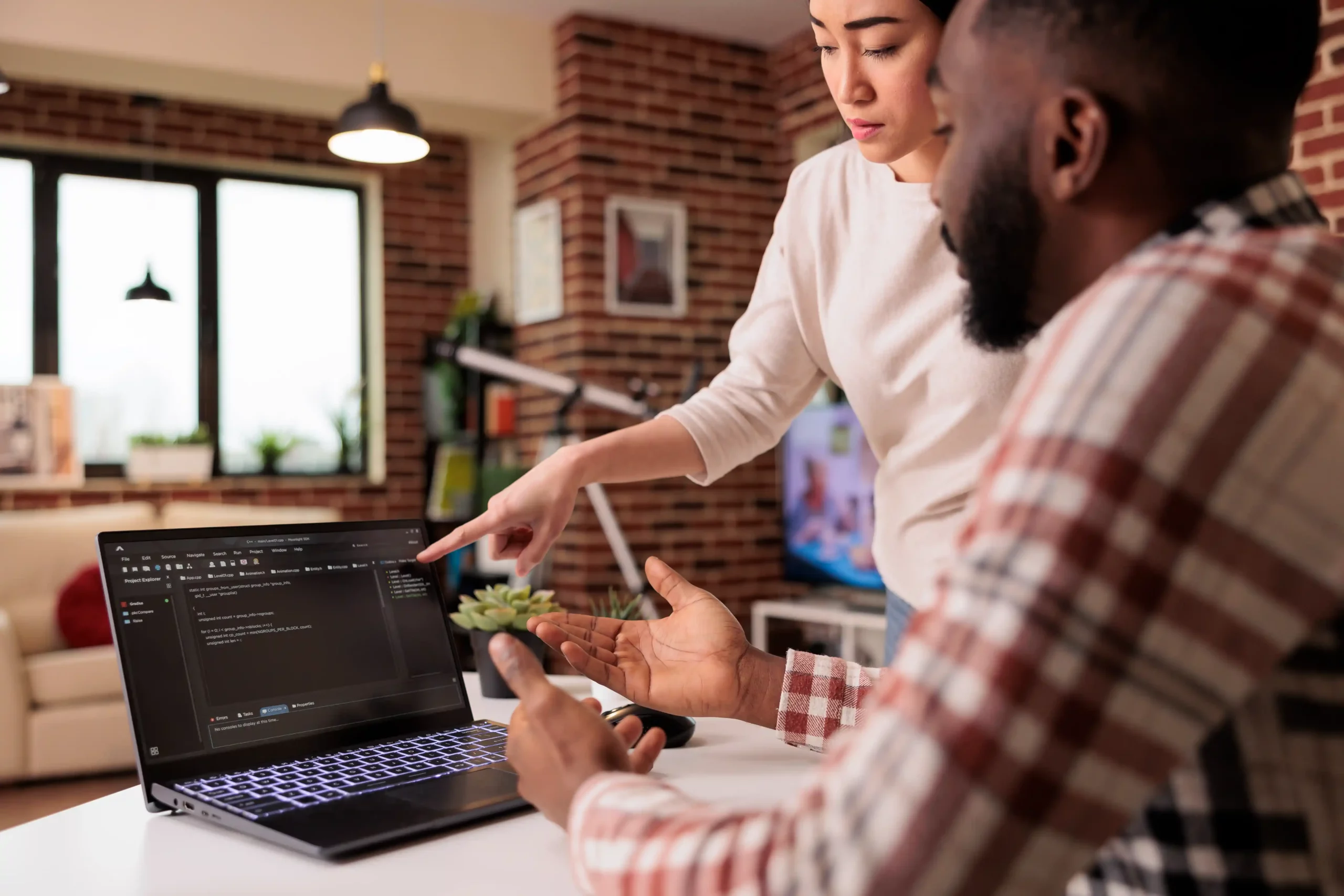 Digital Marketing Agency A woman points at a laptop screen with code on it while a man sits beside her, discussing the content in a modern office setting. Paradox Media